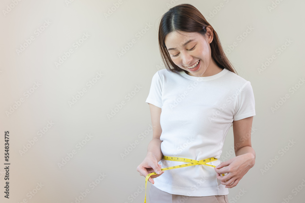 Young slim woman measuring her waist by measure tape after a diet. Young slim woman measuring her waist by measure tape after a diet.