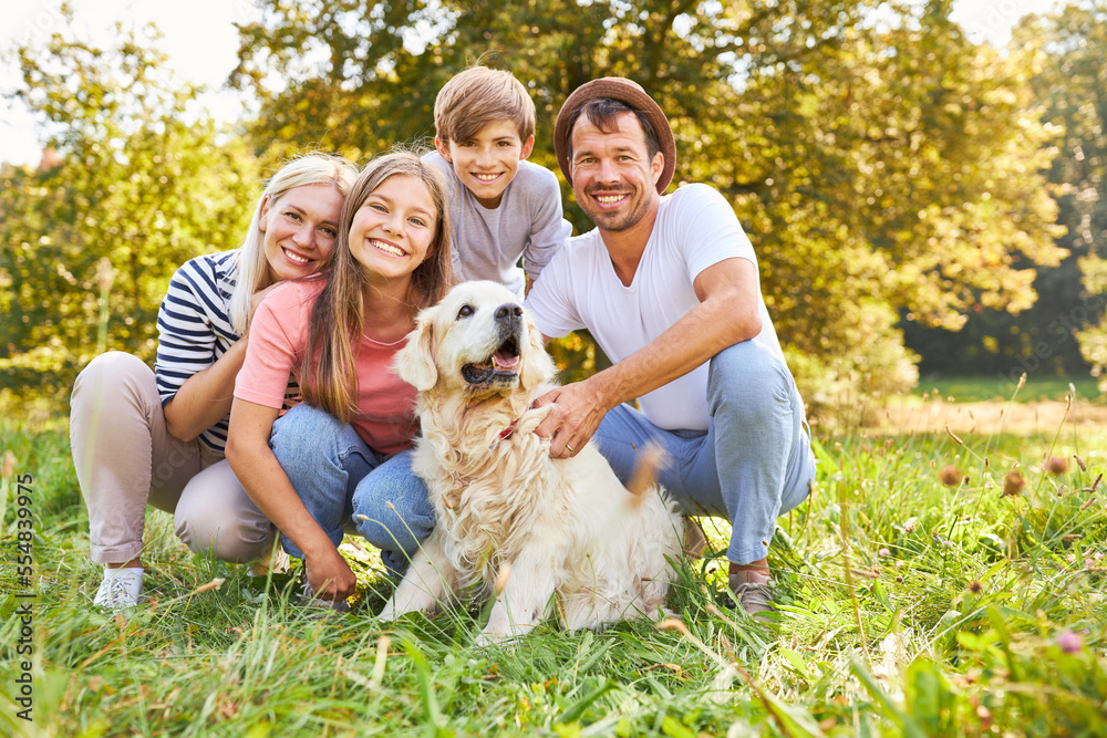 Glückliche Familie mit zwei Kindern und Hund im Park Glückliche Familie mit zwei Kindern und Hund im Park