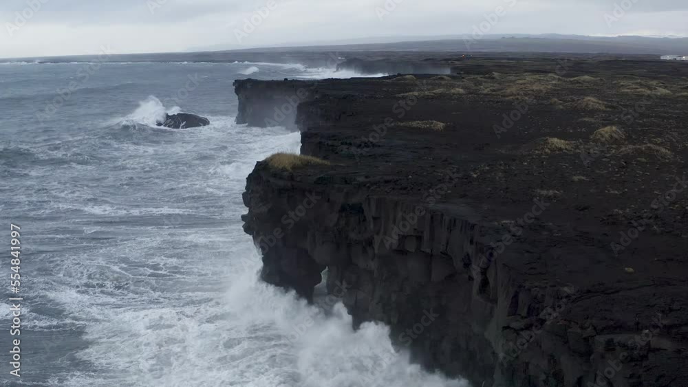 Waves Crashing against basalt sea cliffs on Icelandic coastline in autumn - aerial view Waves Crashing against basalt sea cliffs on Icelandic coastline in autumn - aerial view