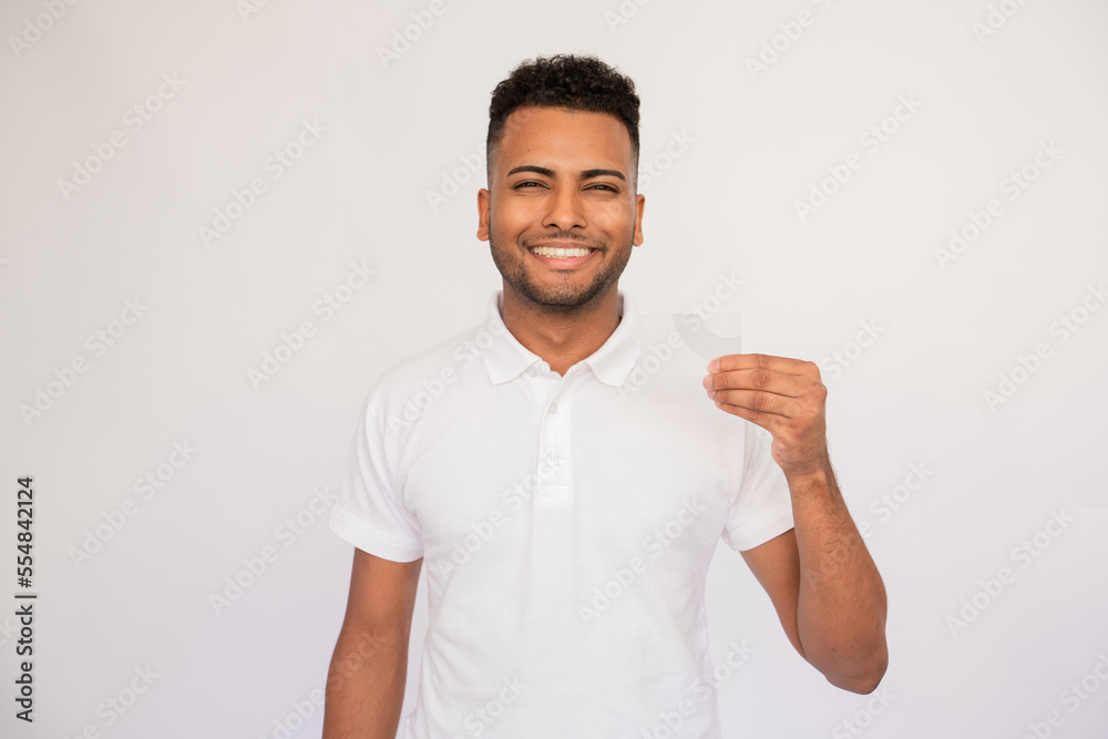 Joyful young man presenting business card. Male Indian model with brown eyes and curly hair in casual clothes smiling showing business card in his hand. Advertising, business concept Joyful young man presenting business card. Male Indian model with brown eyes and curly hair in casual clothes smiling showing business card in his hand. Advertising, business concept