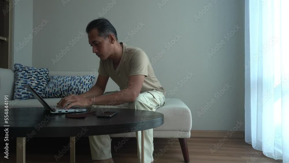 Concept idea Asian business man using laptop while Sitting in the coach of living room. Working from home Concept idea Asian business man using laptop while Sitting in the coach of living room. Working from home