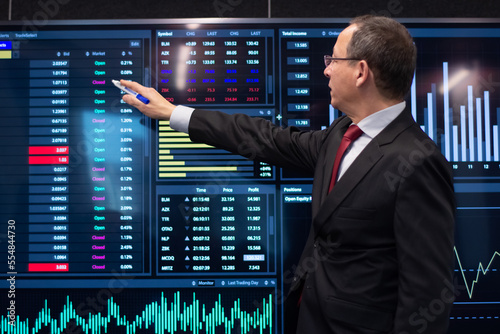 Financial expert working with stock market data. Serious man in formalwear standing near digital display showing currency growth with marker and analyzing trends. Financial analytics, business concept