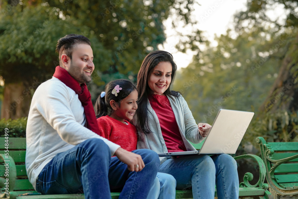 Indian family using laptop at park Indian family using laptop at park