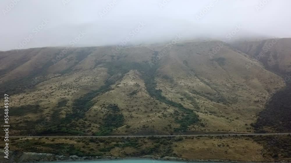 aerial view of the calm sea next to mount cook with fog at the top and the road, new zealand aerial view of the calm sea next to mount cook with fog at the top and the road, new zealand