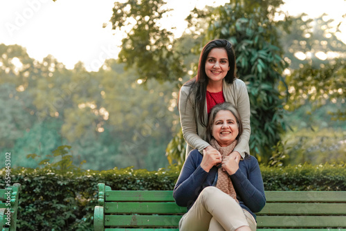 Two indian woman sitting at park in winter wear