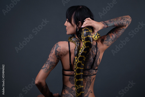 Image of the woman from back holding anaconda along the spine
