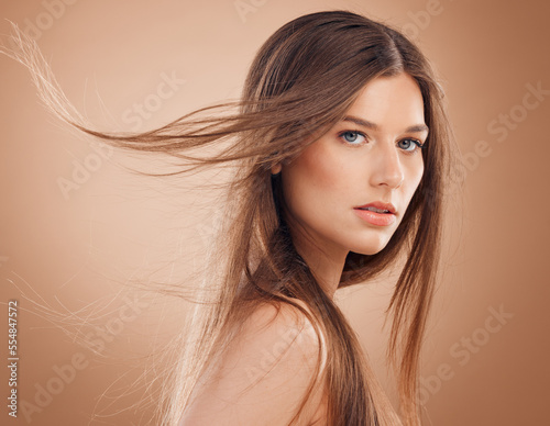 Woman, face glow or windy hair on studio background in keratin treatment, dermatology health, care or collagen wellness. Portrait, brunette beauty model or facial makeup cosmetics for Canada skincare