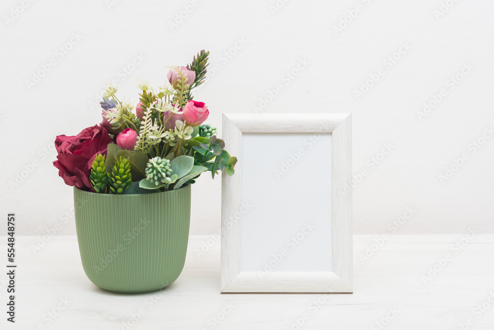 Blank picture frame mockup on white cupboard. White living room design. Home staging and minimalism concept Blank picture frame mockup on white cupboard. White living room design. Home staging and minimalism concept
