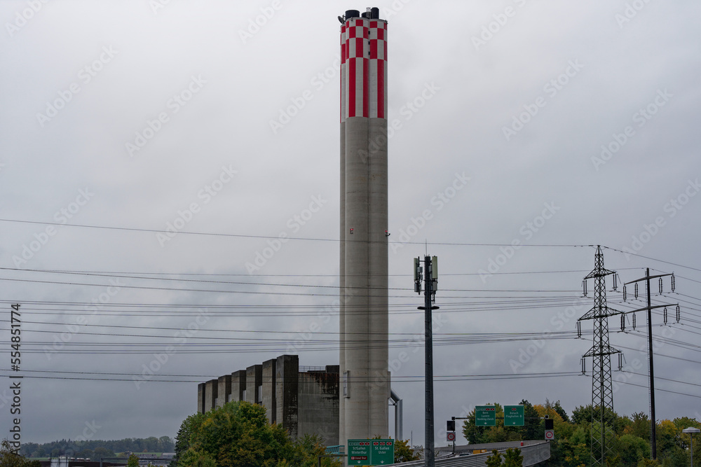 Obraz premium Chimney of power plant with power line cables and pylons at City of Zürich on a cloudy rainy autumn day. Photo taken October 1st, 2022, Zurich, Switzerland.