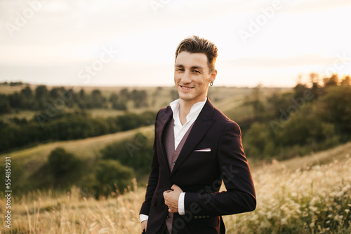 Handsome young groom in a suit posing in nature