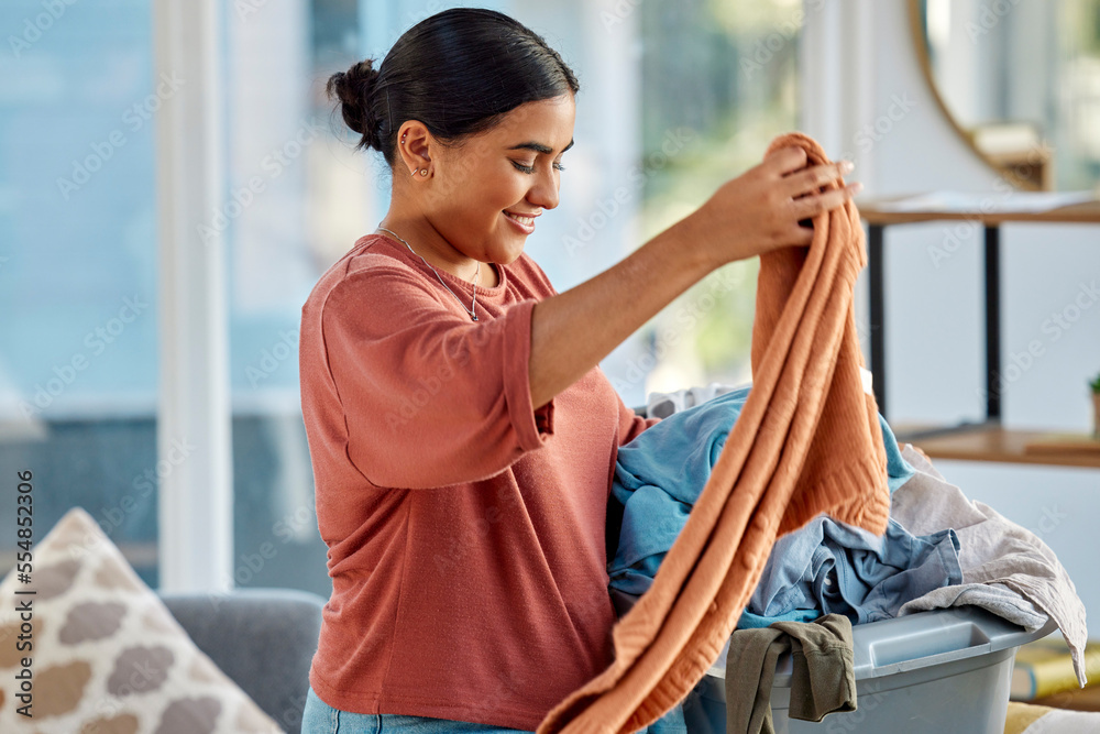 Cleaning, laundry basket and woman with clothes in home getting ready to  wash clothing. Spring cleaning, hygiene and happy female preparing for  fabric washing, housework or chores in living room. Stock Photo