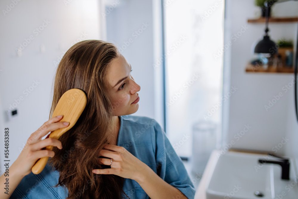 Young woman taking care of her hair, morning beauty routine concept. Young woman taking care of her hair, morning beauty routine concept.