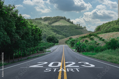 Happy new year 2023,2023 symbolizes the start of the new year. The letter start new year 2023 on the road in the nature route roadway have tree environment ecology or greenery wallpaper concept.