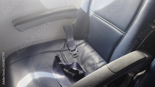 Empty plane window seat with unbuckled seatbelt photo