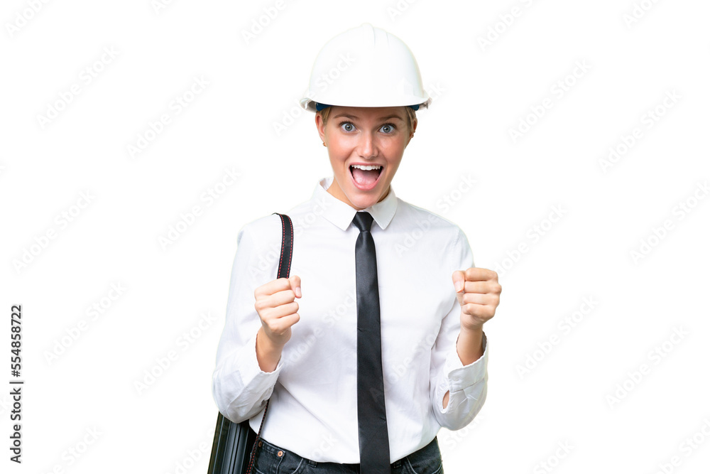 Young architect caucasian woman with helmet and holding blueprints over isolated background celebrating a victory in winner position