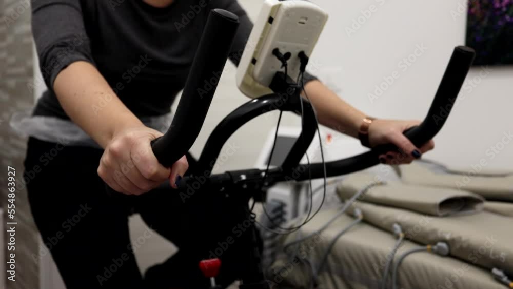 Girl rides on an exercise bike in a beauty center. No face. Girl rides on an exercise bike in a beauty center. No face.