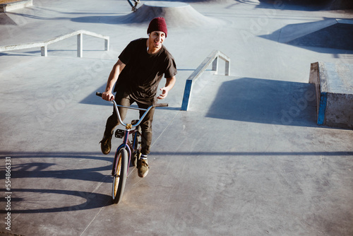 Young man doing BMX trick. Teenager at skatepark riding a BMX bike. Teenager having fun at skatepark.