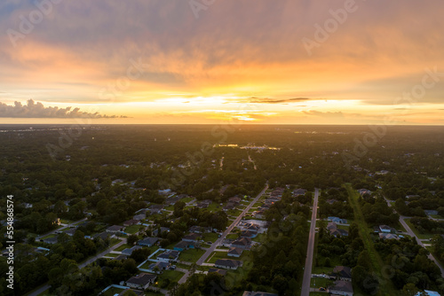 Aerial view of suburban landscape with private homes between green palm trees in Florida quiet residential area in evening