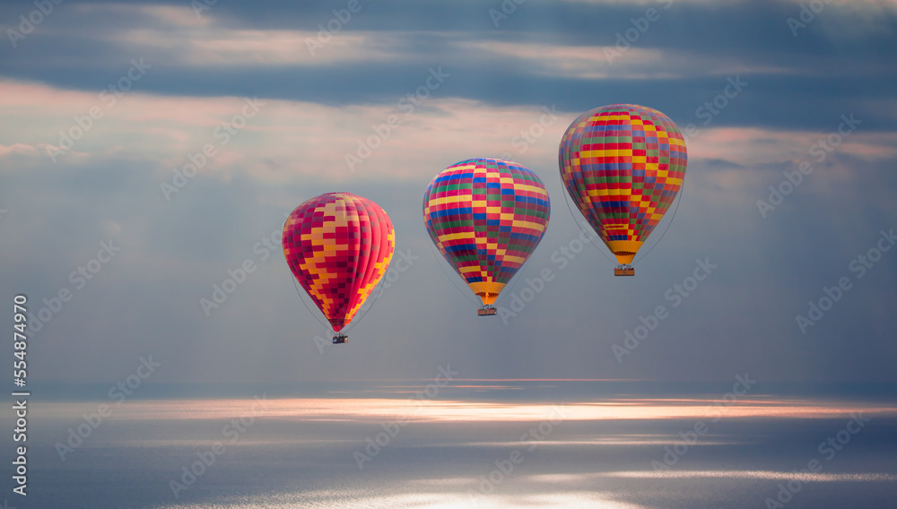 Fototapeta premium Colorful hot air balloon fly over the blue sea at sunset