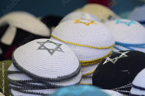 Black  and white with star David traditional jewish yarmulke piles. Kippah with words pray for sale at the market.  photo