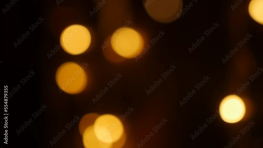 Defocused holiday lights glowing in darkness in night city streets. Abstract christmas background in bokeh. Blinking garland in blur. Out of focus Defocused holiday lights glowing in darkness in night city streets. Abstract christmas background in bokeh. Blinking garland in blur. Out of focus