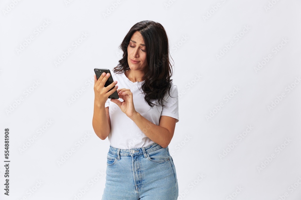 Woman blogger with a phone in her hands photo content, video call, selfie smile with teeth in a white t-shirt on a white background, copy space, emotions and gestures signals Woman blogger with a phone in her hands photo content, video call, selfie smile with teeth in a white t-shirt on a white background, copy space, emotions and gestures signals