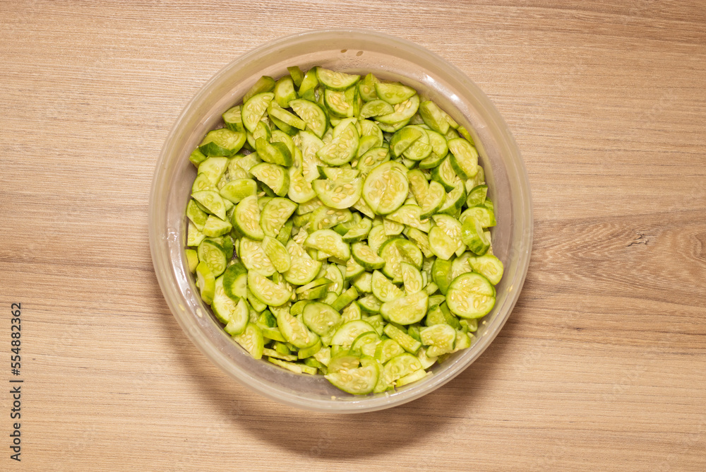 Maxixe sliced with seed. Container on wooden table Maxixe sliced with seed. Container on wooden table