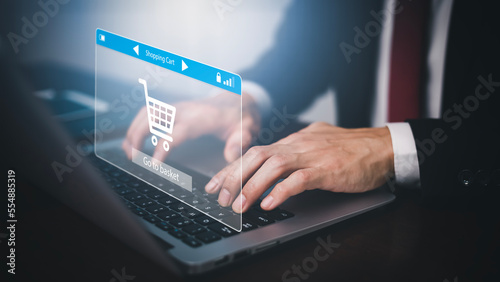 Man using a laptop with typing on a keyboard with online shopping concept, Shopping cart part of the network in hand, Innovation in eCommerce, Online shopping business with selecting shopping cart.