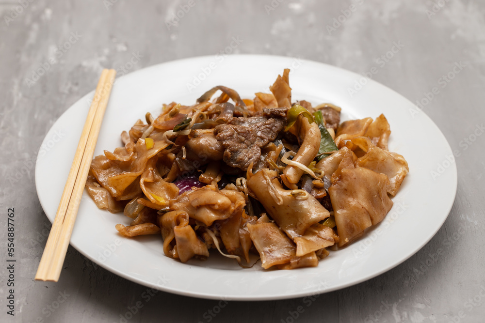 Fried noodles with vegetables and beef in white dish