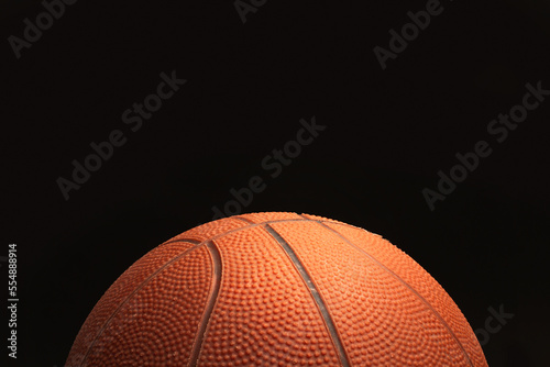 Pelota de baloncesto sobre un fondo negro  liso y aislado. Vista de frente y de cerca. Copy space © Mercedes Fittipaldi