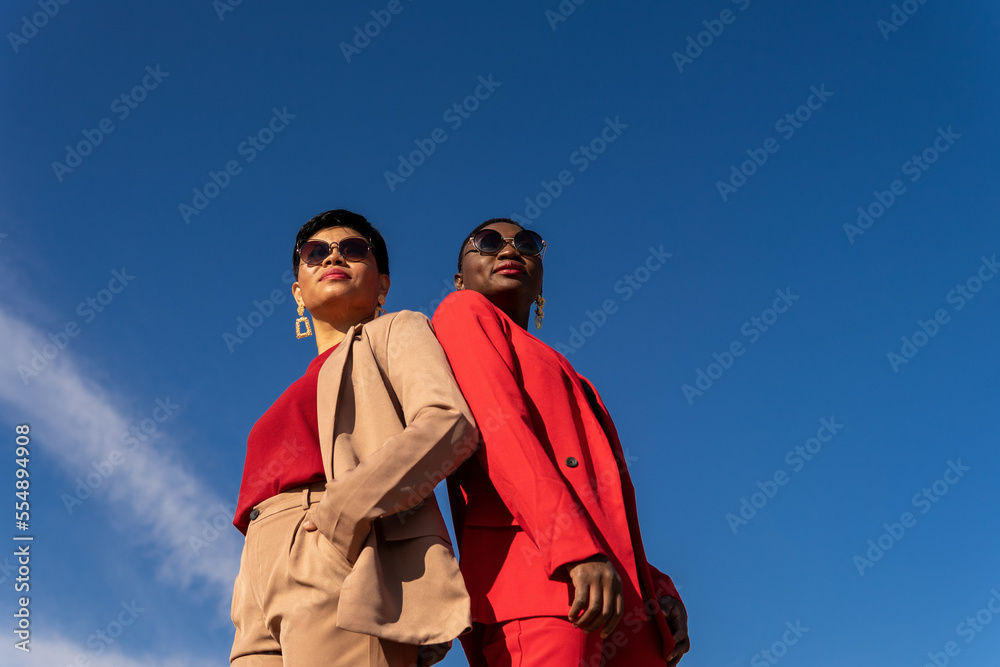 Confident elegant diverse ladies standing under blue sky Confident elegant diverse ladies standing under blue sky