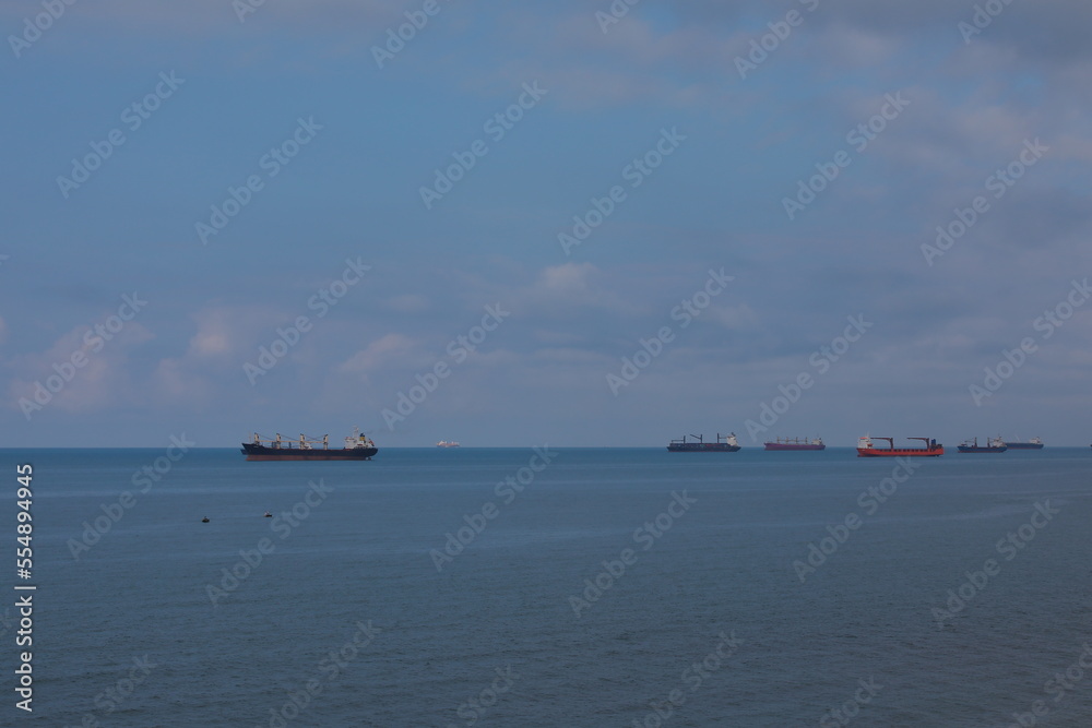 Background image of the sea with many cargo ships in the port and a small fishing boat Background image of the sea with many cargo ships in the port and a small fishing boat