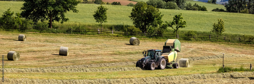 Obraz premium Heuernte, Traktor mit Rundballenpresse