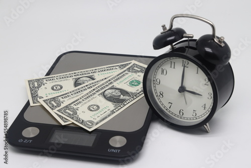 Time is money concept. Clock and money on different scales.