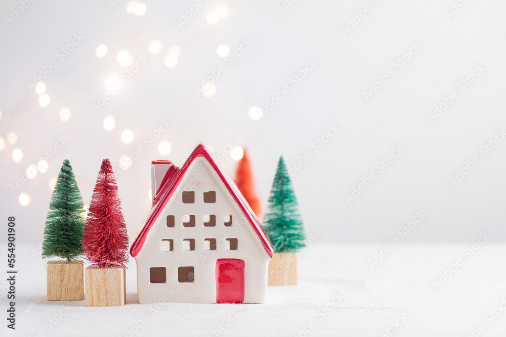 Ceramic christmas house with spruce on the white background with lights