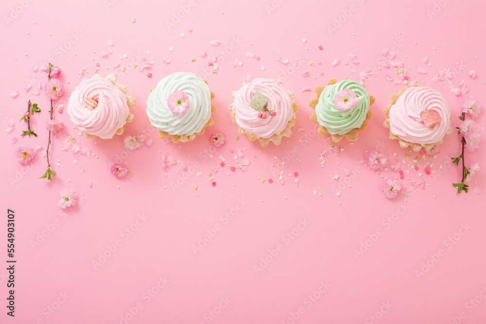 pink and green cupcakes with spring flowers on pink background pink and green cupcakes with spring flowers on pink background