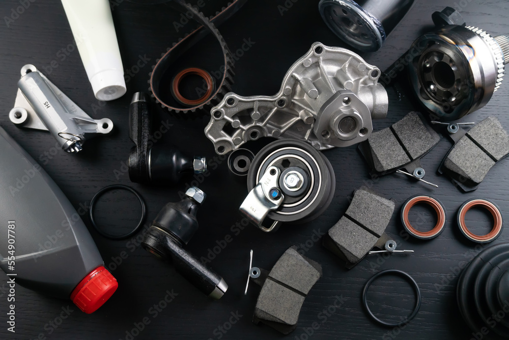 Lot of auto parts lie on wooden black background. Engine and suspension parts, swivel knuckle, joint and engine parts unfolded. New spare parts. Bearings . Play by light. Hanging on table. Lot of auto parts lie on wooden black background. Engine and suspension parts, swivel knuckle, joint and engine parts unfolded. New spare parts. Bearings . Play by light. Hanging on table.