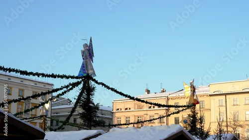 Christmas angel and doves on a snowy winter day against the blue sky, light installation of garlands in the form of an angel on the city square Main Market in Krakow. Polish Christmas Traditions