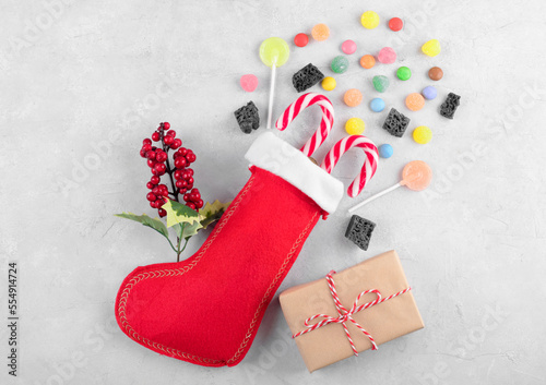 Obraz na plátně Red Epiphany Befana's stocking with sweet coal and candy on light gray background, Italian Epiphany day tradition for children to give a stocking full of sweets