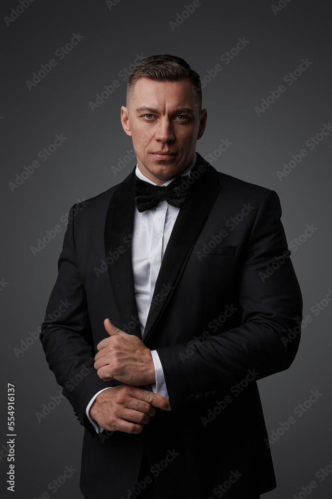 Portrait of handsome man dressed in stylish black suit staring at camera.