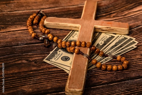 Konstfotografi A Catholic cross, a rosary with beads and dollars lie on a dark brown wooden table