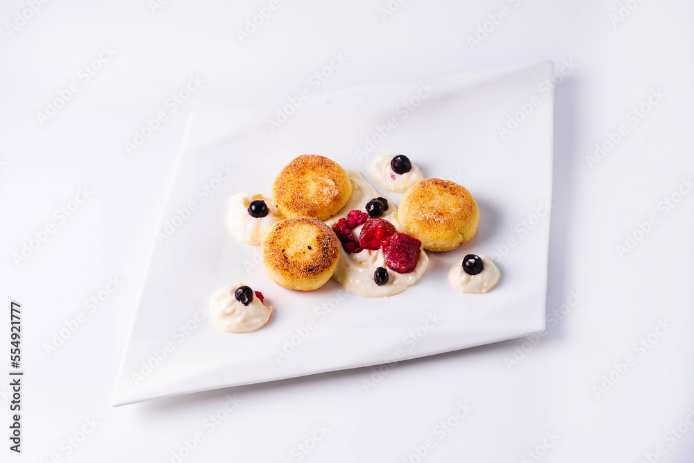 breakfast. cheesecakes with sour cream, strawberries and berries in a white plate on a white background breakfast. cheesecakes with sour cream, strawberries and berries in a white plate on a white background