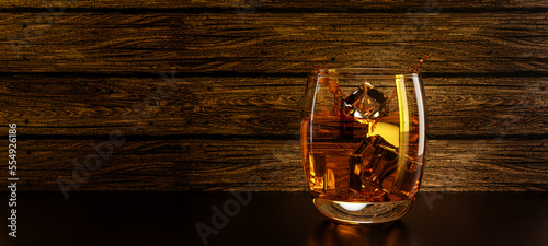 Glass of scotch on the rocks whisky / brandy and ice cubes splash splashing back lit against a wood wooden board background