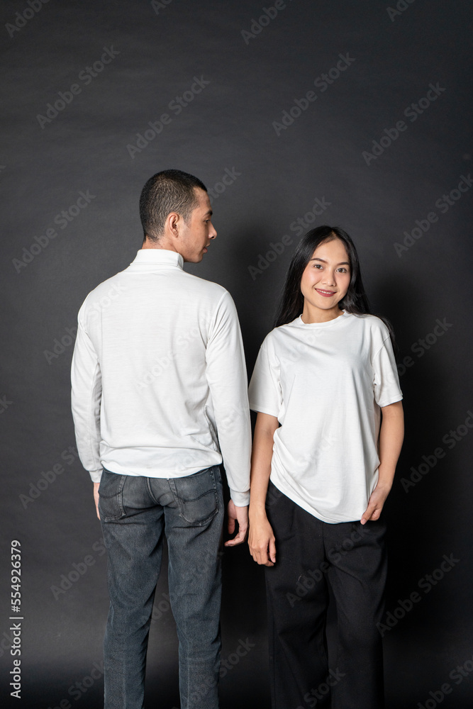 Young couple wearing white blank shirt doing a pose with a black background Young couple wearing white blank shirt doing a pose with a black background