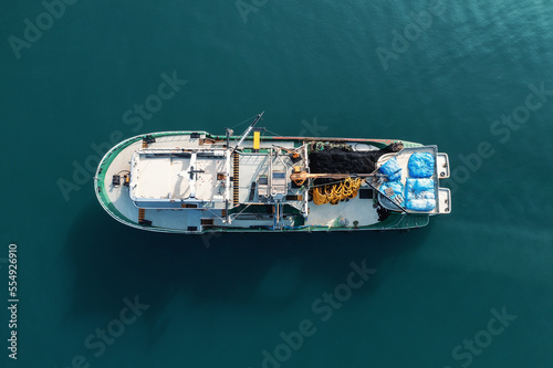 Fishing boat aerial top view from drone on sea surface. Fishing and seafood industry. © DedMityay