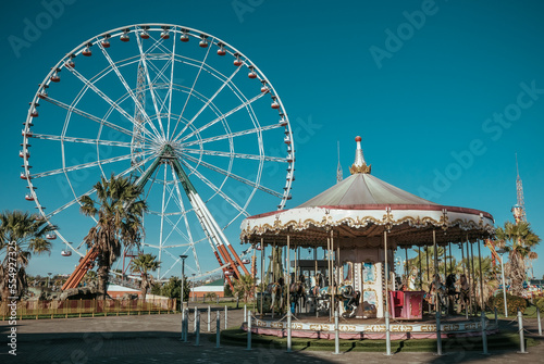 Ferris wheel and empty rides in old vintage amusement park without people.