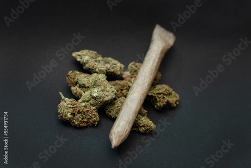 Cogollos de marihuana indica en un fondo negro con un cigarro o porro organico