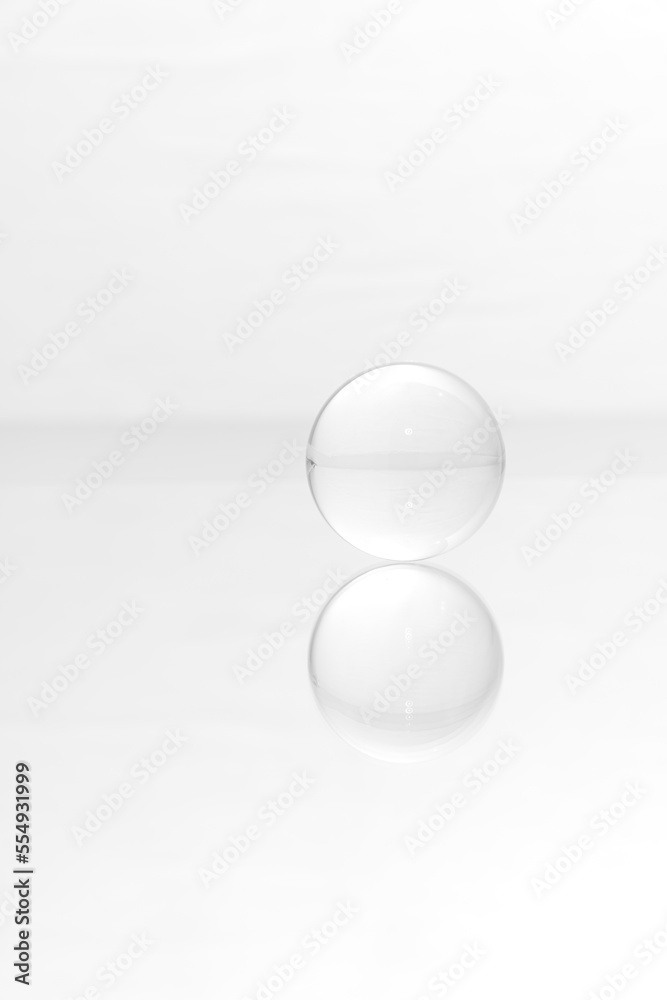 Glass ball on a mirrored surface and white background. Glass ball on a mirrored surface and white background.