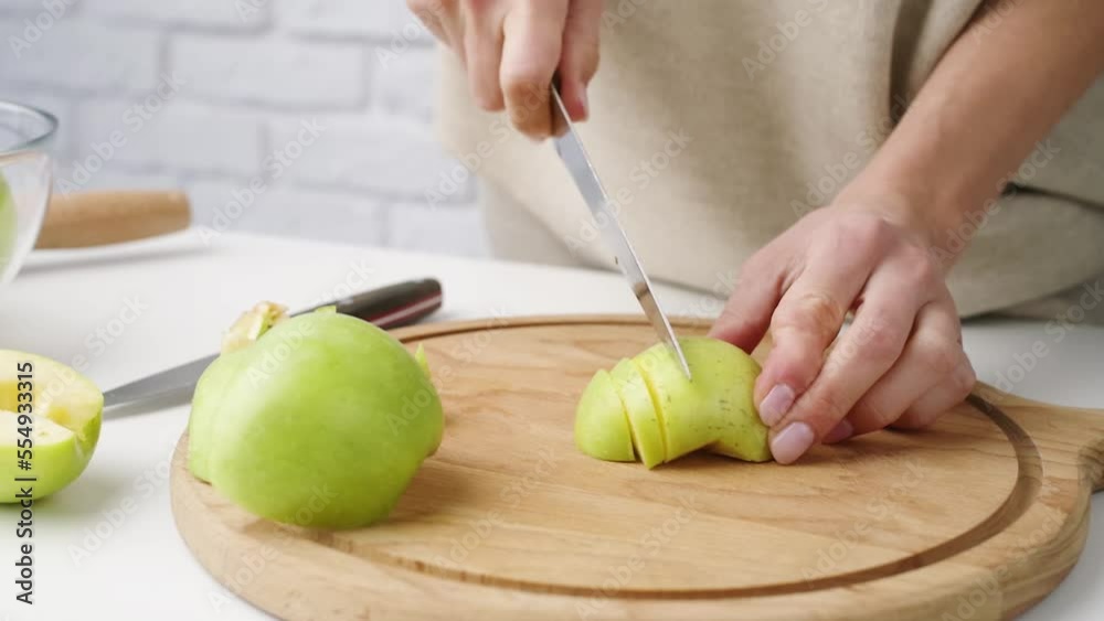 Woman in home clothes cutting apples on cutting board in the kitchen. Preparing healthy food. Hands holding knife and slicing fruits on table in kitchen Woman in home clothes cutting apples on cutting board in the kitchen. Preparing healthy food. Hands holding knife and slicing fruits on table in kitchen