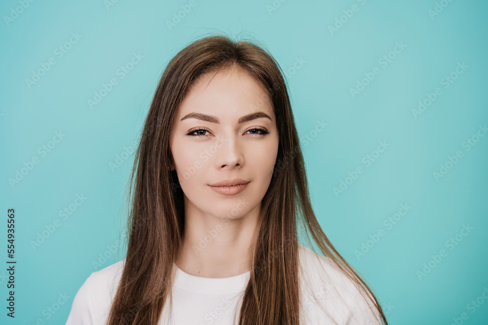 Close up portrait of confident caucasian woman with healthy skin, looking at camera over turquoise studio background. Swedish young successful female in white t-shirt, mockup beauty and healthcare.